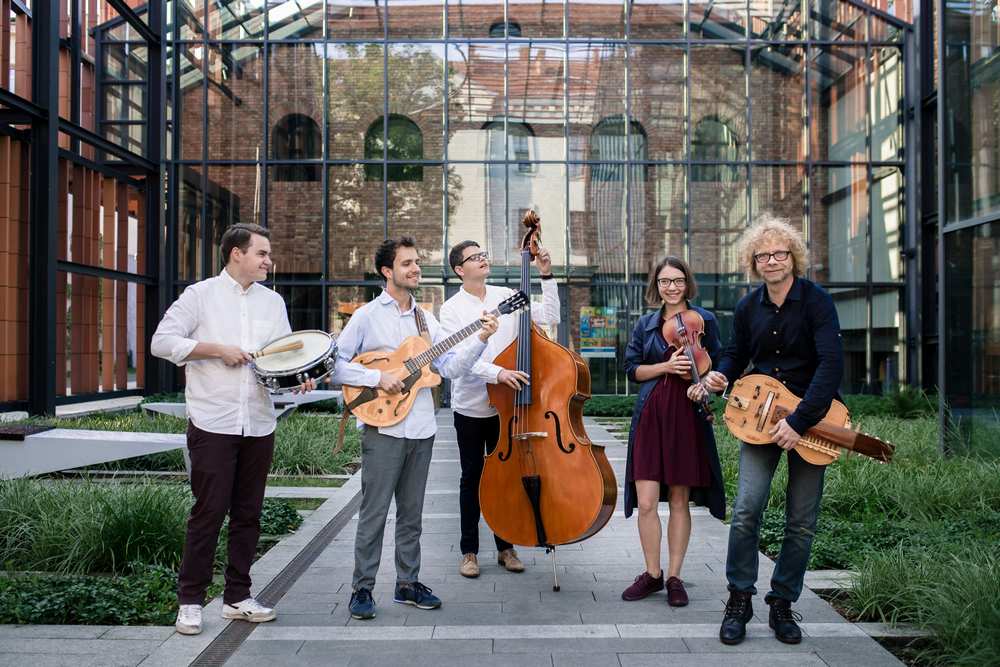 fotografia grupa muzyków stojących obok siebie z instrumentami w budynku o cechach industrialnych